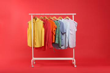 Bright clothes hanging on rack against red background. Rainbow colors