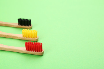 Natural bamboo toothbrushes on green background. Space for text