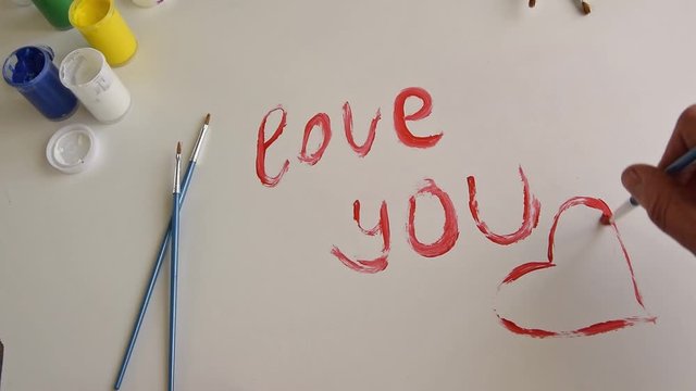 Top view of woman hand painting "I love you" text on white background, artistic creative occupation, love concept