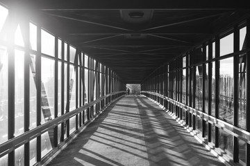 pedestrian pathway above highway, golden light shining creating shadows. Black and white.