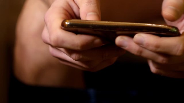 Close up man sitting on toilet with cell smart phone. Gaming mobile games. Chatting on phone