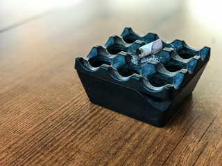 black ashtray and extinguished cigarette on the black table