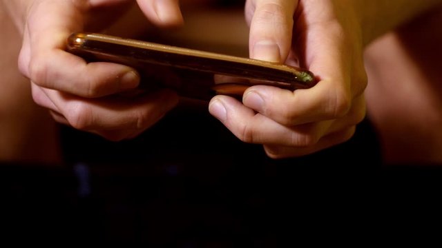 Close up man sitting on toilet with cell smart phone. Gaming mobile games. Chatting on phone