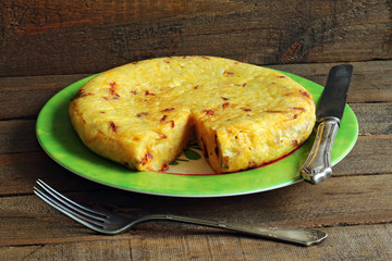 Potato omelette on plate and wooden background
