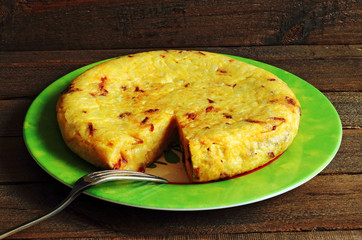 Potato omelette on plate and wooden background
