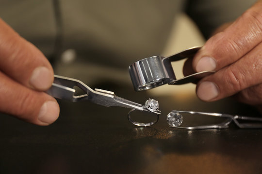 Professional jeweler working with beautiful ring at table, closeup - Powered by Adobe