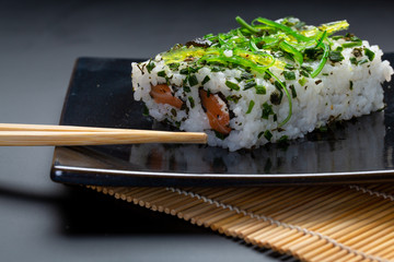 Black plate with sushi, maki and american rolls