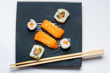 Black plate with sushi, maki and american rolls