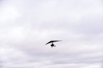 Obraz premium Person flying away into the horizon on a small aircraft single seat microlight as a hobby or sport in the air