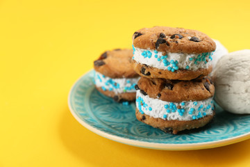 Sweet delicious ice cream cookie sandwiches on yellow background, closeup