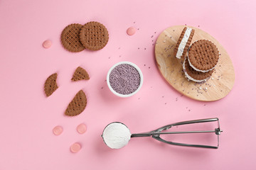 Sweet delicious ice cream cookie sandwiches on pink background, flat lay