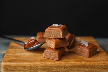 Delicious salted caramel on wooden board, closeup