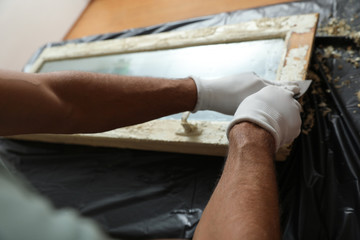 Fototapeta na wymiar Man repairing old damaged window at table indoors, closeup