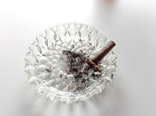 An extinguished cigar in an ashtray isolated on a white background.