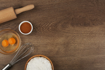Flat lay composition with raw eggs and other ingredients on wooden table, space for text. Baking pie