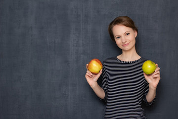 Portrait of happy young woman smiling and holding two apples in hands
