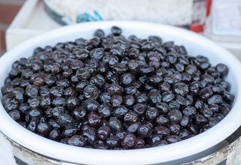 Pickled black olives in bucket close-up. It was filmed in front of a shop.