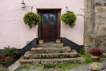 Solid wooden front door at the top of stone steps in the pretty Devon village of Dunsford © steheap