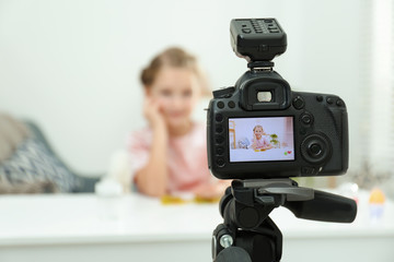 Cute little blogger with slime recording video at home, focus on camera