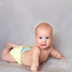 Cute little baby smiling and relaxing in bright bedroom. Health and care of little children. Family, motherhood, love, innocence, emotion.