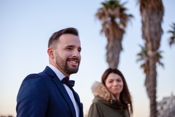 Young woman looking weird at a young attractive man with a beard dressed in a suit and tie smiling