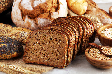 Assortment of baked bread and bread rolls and cutted bread on table background