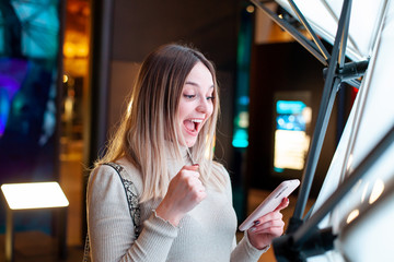 Happy beautiful caucasian young girl celebrating with smartphone in her hand