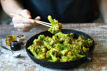 Broccoli cooked in a pan. Healthly food. A man with chopsticks eats broccoli.