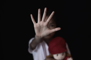 Child showing hand signaling to stop useful to campaign against violence and pain on dark background