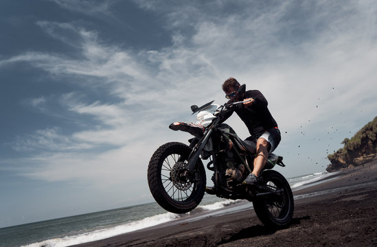  Man ride on the motorbike at the ocean black sand beach © Photo-maxx