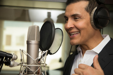 actor and radio announcer with headphones and microphone working film dubbing, performing radio spot and singing