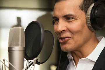 actor and radio announcer with headphones and microphone working film dubbing, performing radio spot and singing