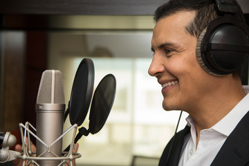 actor and radio announcer with headphones and microphone working film dubbing, performing radio...