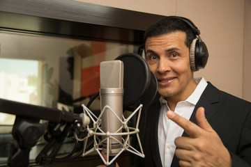 actor and radio announcer with headphones and microphone working film dubbing, performing radio...