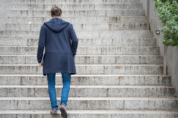 Young man Holding Computer Laptop Walking Up Stairs outdoor .