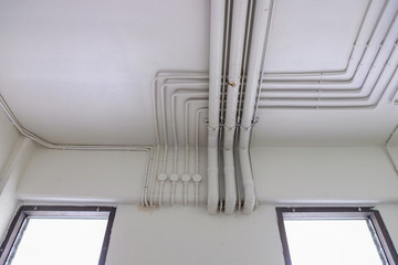 Electrical system pipes and water system pipes. White electric PVC pipes line or Wiring rails in the building
