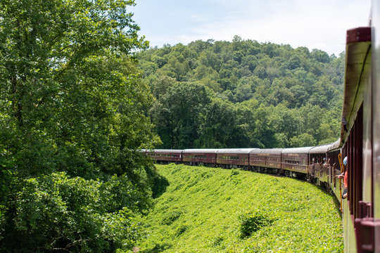 A horizontal, landscape orientation of a train making a big turn through the mountains and rural countryside of North Carolina.