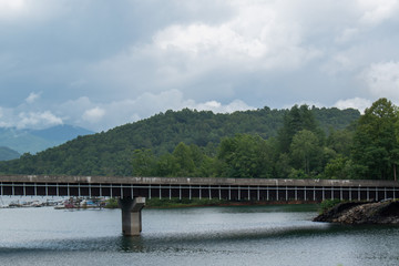 Obraz premium A railroad bridge in the distance with a river flowing underneath in the mountains of North Carolina.