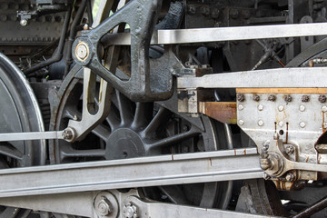 The silver and black metal shine in a close up of a steam engine wheel