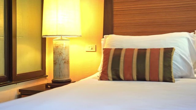 Pan from glass divider across hotel bed.