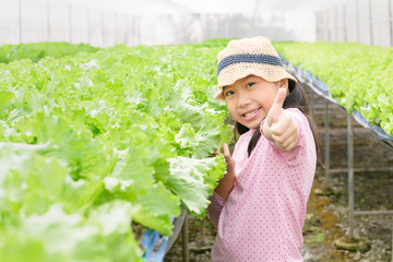 Cute asian girl showing thumb up at organic vegetable farm