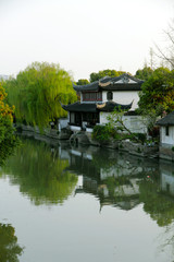 Fototapeta na wymiar Traditional green houses with green weeping willows and white walls and black tiles form the spring scenery of the ancient canal in Jiangnan, China