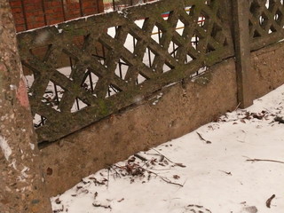 old concrete fence in the form of a grid  in winter.