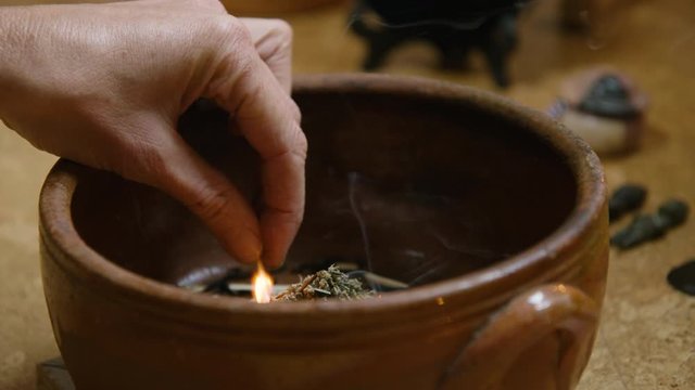 A womans hands light incense before offering smoke to the Ancestors CU