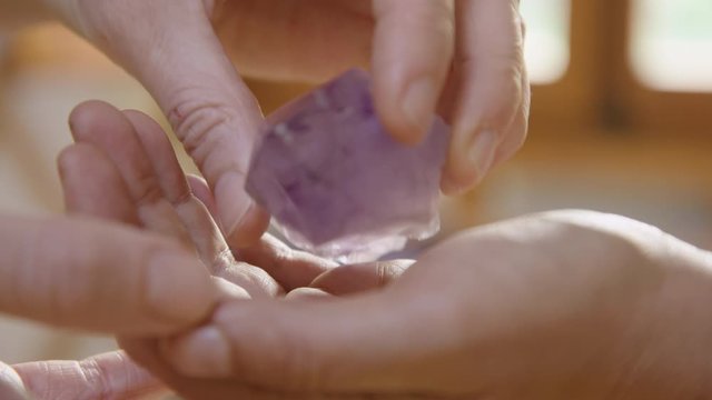 ECU of a purple Amethyst crystal being handed to a client in a healing yurt. 60fps