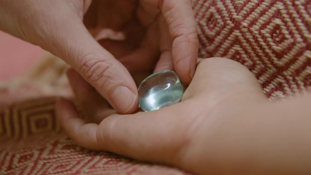 A clear obsidian crystal is placed in a clients hand during crystal therapy