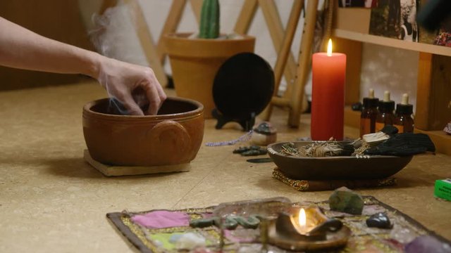 A womans hands light incense before offering smoke at the Ancestor Altar