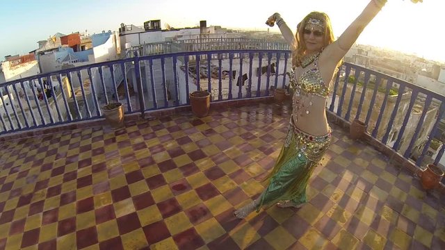 Beautiful shot of belly dancer at sunset on a rooftop in Morocco at sunset.