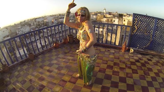 Slow motion of belly dancer at sunset dancing on rooftop in Essaouira, Morocco.
