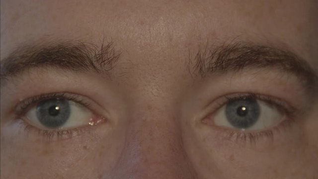 Close up of pair of blue male eyes looking around and blinking slowly